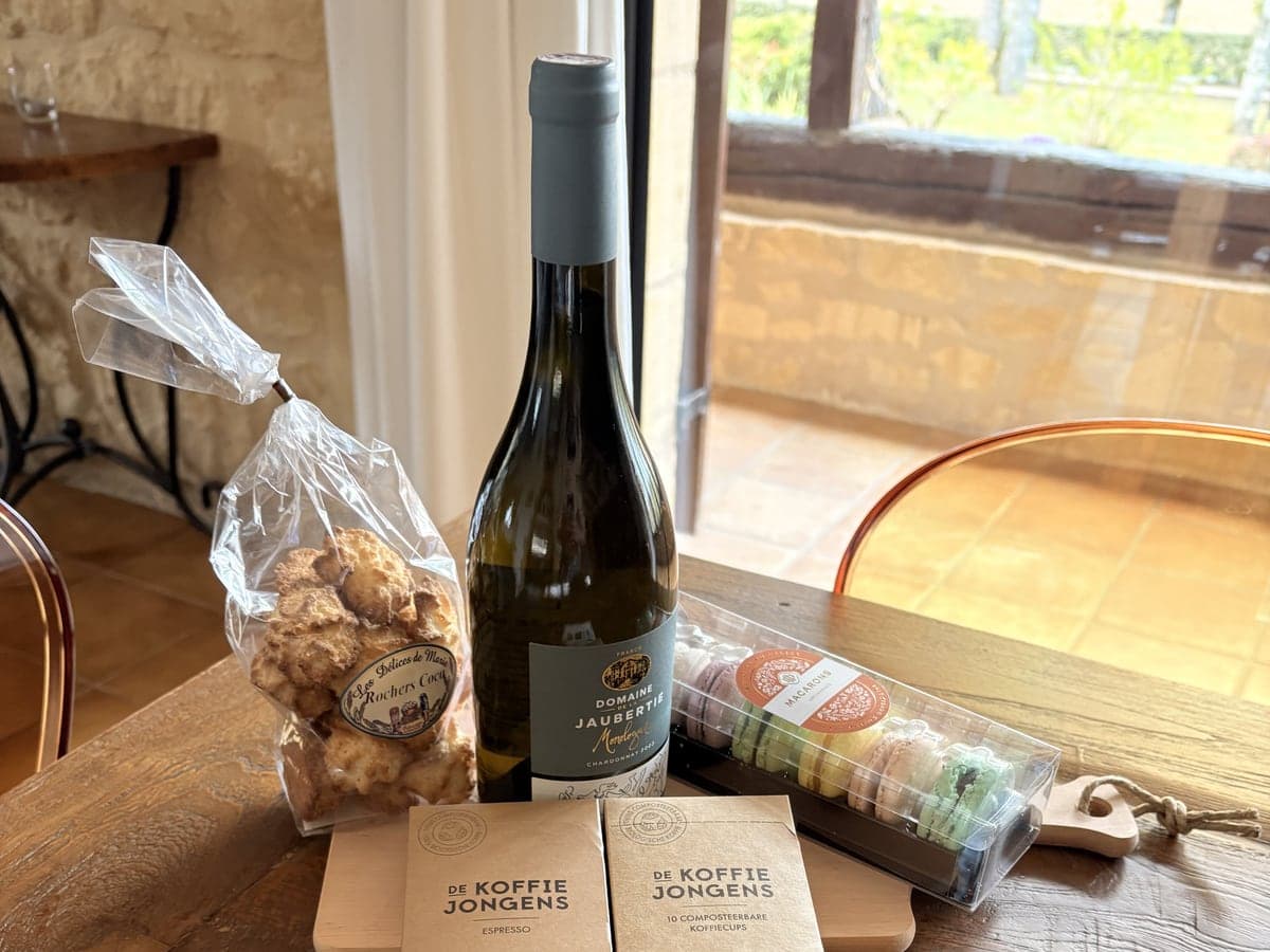 A Dordogne Collection welcome arrangement: local wine, artisanal coffee and macarons on a wooden table